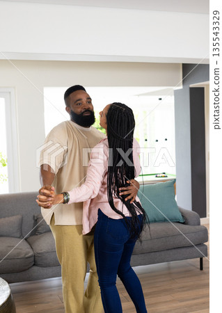 African American couple dancing joyfully in living room, sharing happy moment African American couple dancing joyfully in living room, sharing happy moment 135543329