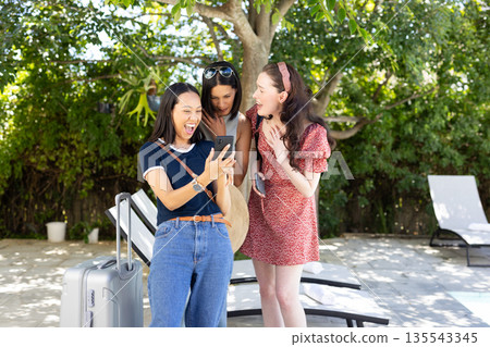 Laughing and sharing moment, three young women gather around smartphone outdoors Laughing and sharing moment, three young women gather around smartphone outdoors 135543345