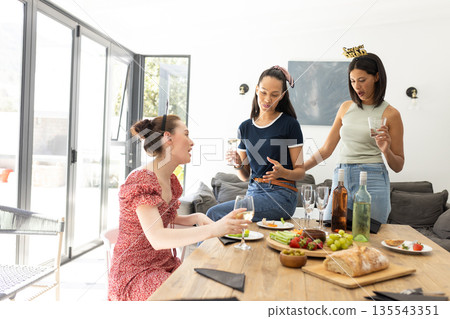 Chatting and laughing, three young women enjoy sunny afternoon at home Chatting and laughing, three young women enjoy sunny afternoon at home 135543351