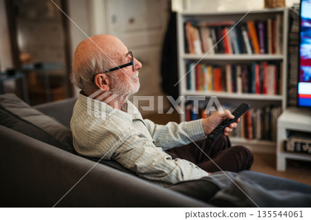 Elderly man watching television alone at home. Elderly man watching television alone at home. 135544061