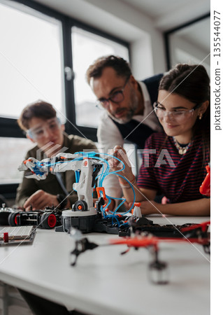 High school students working on robotics project with their teacher. High school students working on robotics project with their teacher. 135544077