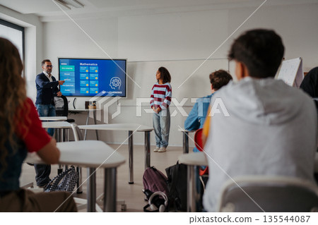 Teen girl presenting AI learning project in classroom. 135544087