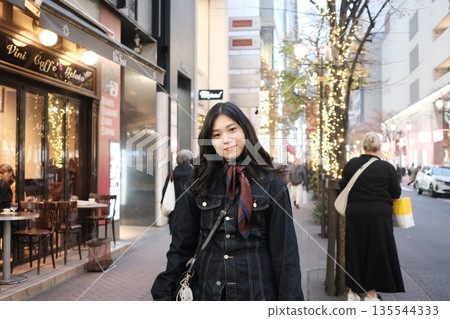 Woman standing on an illuminated city street at night 135544333