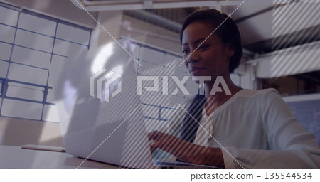 Typing woman in white blouse working on silver laptop at modern loft-style office desk, copy space Typing woman in white blouse working on silver laptop at modern loft-style office desk, copy space 135544534