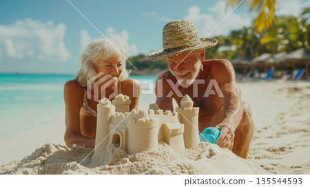 Senior couple with grandchild building sandcastles on beach 135544593