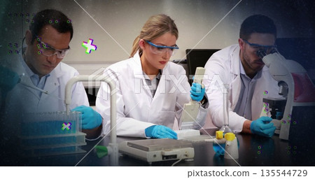 Female scientist wearing lab coat pipetting into microplate at bench, with multi-channel pipette 135544729
