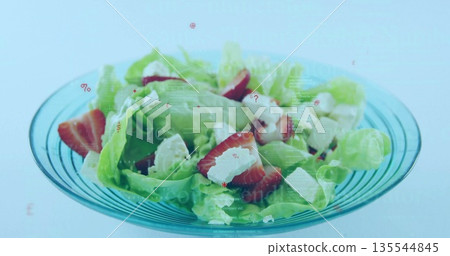 Displaying clear glass bowl filled with lettuce, strawberries and crumbled cheese on studio surface Displaying clear glass bowl filled with lettuce, strawberries and crumbled cheese on studio surface 135544845