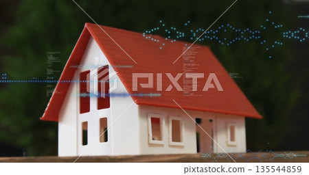 Displaying scale model house featuring red roof white walls on wooden table with digital overlay 135544859