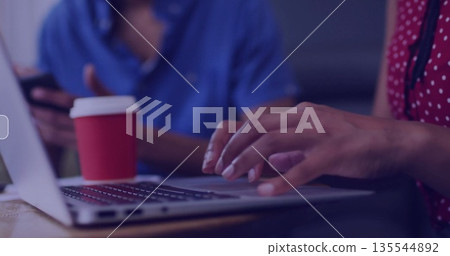 Woman in red polka-dot top working on laptop at cafe table, with smartphone and coffee cup Woman in red polka-dot top working on laptop at cafe table, with smartphone and coffee cup 135544892