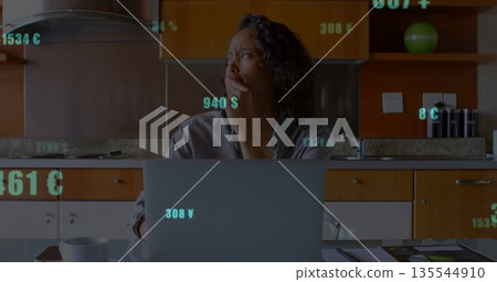 Leaning African-American woman studying laptop at kitchen counter, with floating currency symbols Leaning African-American woman studying laptop at kitchen counter, with floating currency symbols 135544910
