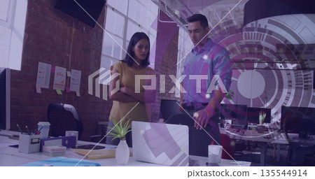 Collaborating, two colleagues reviewing laptop on white desk in modern office with coffee cup Collaborating, two colleagues reviewing laptop on white desk in modern office with coffee cup 135544914
