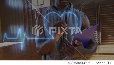Observing fitness coach in hoodie monitoring heartbeat on gym court with whistle and clipboard Observing fitness coach in hoodie monitoring heartbeat on gym court with whistle and clipboard 135544915