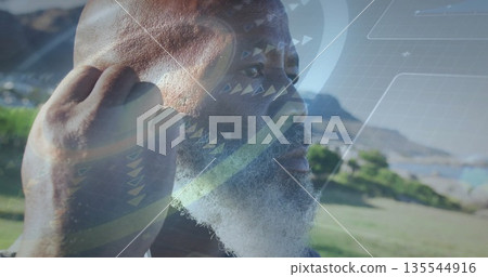 Senior man adjusting wireless earbud in park, with semi-transparent virtual interface overlay Senior man adjusting wireless earbud in park, with semi-transparent virtual interface overlay 135544916