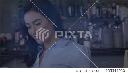 Smiling bartender arranging glassware at bar, with liquor bottles and pink flower vase, copy space Smiling bartender arranging glassware at bar, with liquor bottles and pink flower vase, copy space 135544930