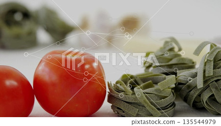 Arranging fresh red tomatoes and green pasta nests at kitchen prep area, with digital data network 135544979