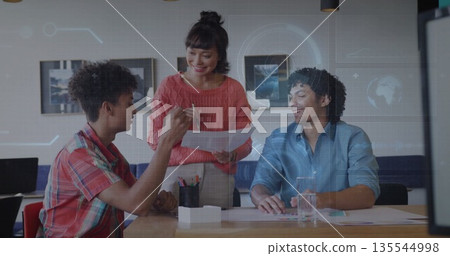 Three professionals collaborating around table in office, with printed documents pen and laptop 135544998
