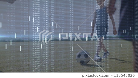 Practicing child soccer players in jerseys kicking soccer ball on grassy field, data overlay Practicing child soccer players in jerseys kicking soccer ball on grassy field, data overlay 135545026