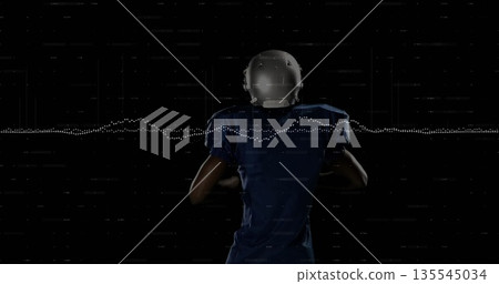 Holding football, player in blue jersey and helmet in studio with waveform and digital scan lines 135545034