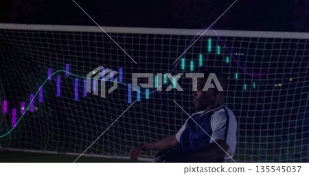 Posing soccer player wearing gear on pitch before goal net with neon candlestick chart, copy space Posing soccer player wearing gear on pitch before goal net with neon candlestick chart, copy space 135545037
