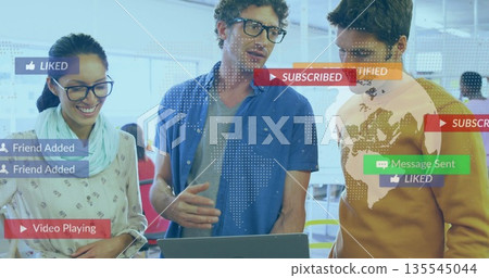 Discussing colleagues reviewing metrics in modern office with laptop floating social media icons 135545044