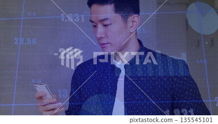 Holding smartphone, Asian adult male in navy shirt analyzing digital charts and graphs in office Holding smartphone, Asian adult male in navy shirt analyzing digital charts and graphs in office 135545101