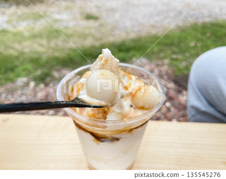 A Japanese parfait of shiratama dumplings and soft serve ice cream topped with soybean flour and brown sugar syrup. A Japanese parfait of shiratama dumplings and soft serve ice cream topped with soybean flour and brown sugar syrup. 135545276