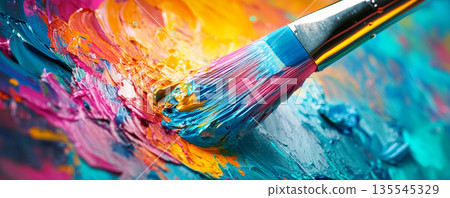 Close-up of paintbrush with vibrant yellow, red, and blue paint strokes 135545329