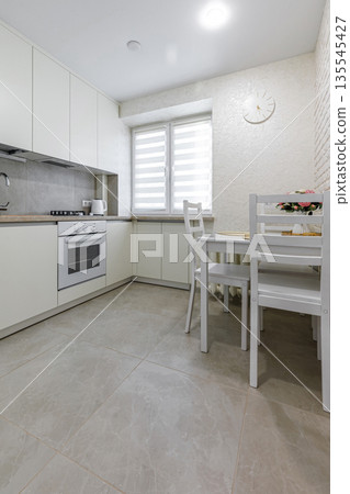 Bright modern kitchen and dining area with white furniture 135545427