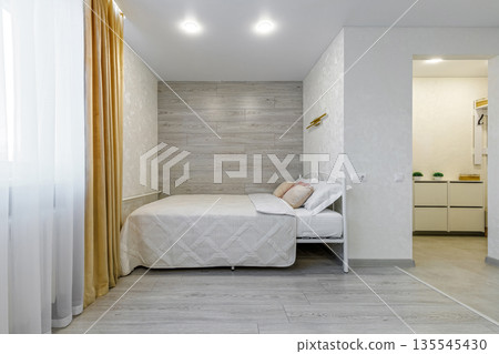Modern studio apartment bedroom area with wooden accent wall and bed 135545430