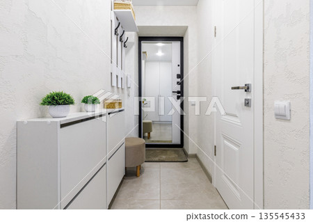 Bright minimalist entryway interior with white shoe cabinet and mirror Bright minimalist entryway interior with white shoe cabinet and mirror 135545433