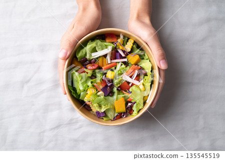 Healthy vegetable salad in takeout bowl with hand, Top view Healthy vegetable salad in takeout bowl with hand, Top view 135545519