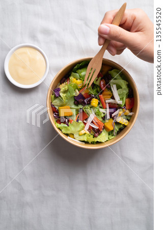 Healthy vegetable salad in takeout bowl eating with salad dressing, Top view Healthy vegetable salad in takeout bowl eating with salad dressing, Top view 135545520