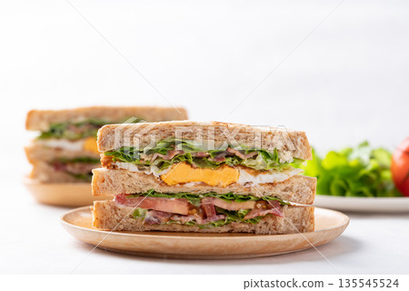 Whole wheat bread sandwich with bacon, lettuce, tomato and fried egg  135545524