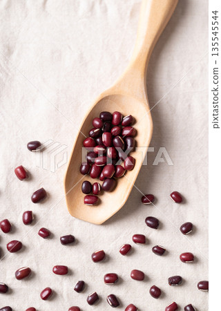 Azuki beans, Adzuki bean or red mung beans in wooden spoon on white fabric background Azuki beans, Adzuki bean or red mung beans in wooden spoon on white fabric background 135545544