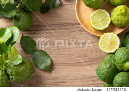 Kaffir lime fruit with leaf on wooden background, Thai food ingredient, Table top view Kaffir lime fruit with leaf on wooden background, Thai food ingredient, Table top view 135545550