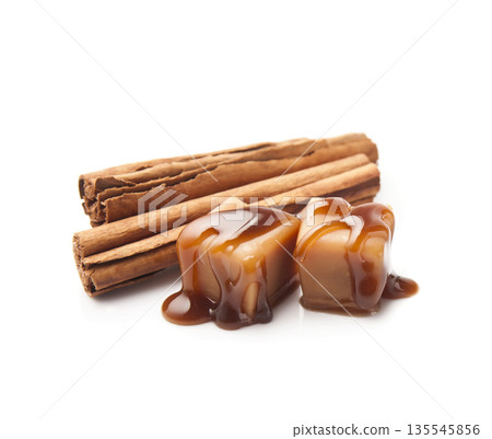 Caramel candy with cinnamon pods on white backgrounds 135545856