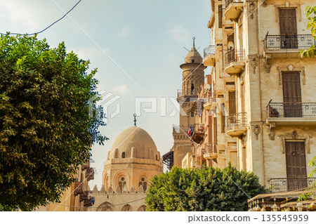 Historic Qalawun Complex in Cairo, featuring intricate architecture, tall minarets, and domes under a blue sky with clouds. A significant cultural landmark on Al-Muizz Street. Historic Qalawun Complex in Cairo, featuring intricate architecture, tall minarets, and domes under a blue sky with clouds. A significant cultural landmark on Al-Muizz Street. 135545959