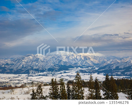 View of the snow-covered Uonuma Basin and the mountain ranges of Mt. Makihata and Mt. Hakkai from a ski resort (Niigata Prefecture, Minamiuonuma, Joetsu Kokusai Ski Resort) 135546276