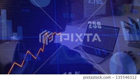 Typing data analyst woman wearing dark top sitting at office desk, with laptop and financial charts Typing data analyst woman wearing dark top sitting at office desk, with laptop and financial charts 135546312