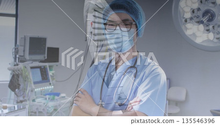 Standing mature Chinese surgeon crossing arms in hospital operating room, with medical monitors Standing mature Chinese surgeon crossing arms in hospital operating room, with medical monitors 135546396