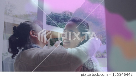 Hugging father and daughter sharing warm embrace at home entrance, with sliding glass door 135546442