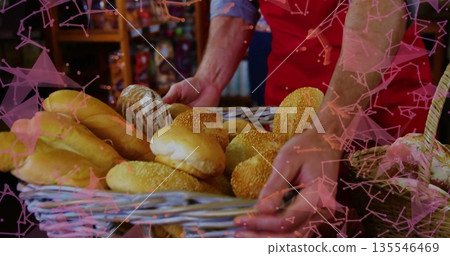 Baker wearing red apron holding wicker basket filled with assorted breads in bakery shop Baker wearing red apron holding wicker basket filled with assorted breads in bakery shop 135546469