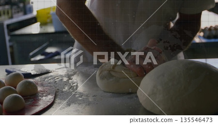 Kneading baker pressing and folding dough on floured counter in bakery, with red tray, scraper Kneading baker pressing and folding dough on floured counter in bakery, with red tray, scraper 135546473