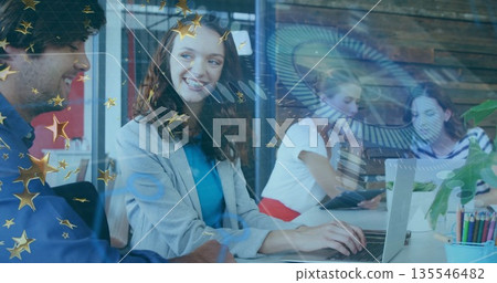 Typing office professional in grey blazer and teal blouse at coworking desk, with laptop and tablet 135546482
