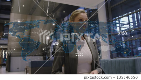 Analyzing holographic map, executive wearing gray blazer in corporate lobby with metal columns Analyzing holographic map, executive wearing gray blazer in corporate lobby with metal columns 135546550