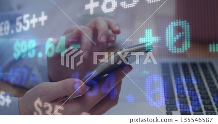 Tapping business person's hands interacting with smartphone on desk, with financial data overlay Tapping business person's hands interacting with smartphone on desk, with financial data overlay 135546587