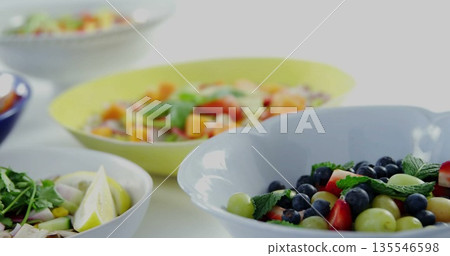 Displaying white and yellow ceramic bowls holding fruit salads on white countertop, copy space Displaying white and yellow ceramic bowls holding fruit salads on white countertop, copy space 135546598