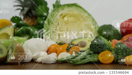 Arranging avocado halves on fresh produce mix over wooden tabletop, showing social media icons 135546694