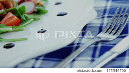 Showing ceramic plate holding salad of arugula, radish, tomato on checked cloth, balsamic droplets Showing ceramic plate holding salad of arugula, radish, tomato on checked cloth, balsamic droplets 135546700