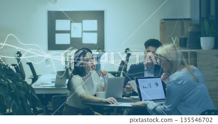Reviewing colleagues analyzing data charts on laptops in conference room, with coffee mug 135546702